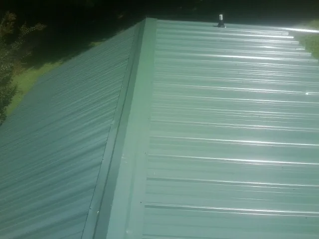 New green metal panels meeting at the ridge of a roof — Flat Roof Repair work by our crew in Wallkill