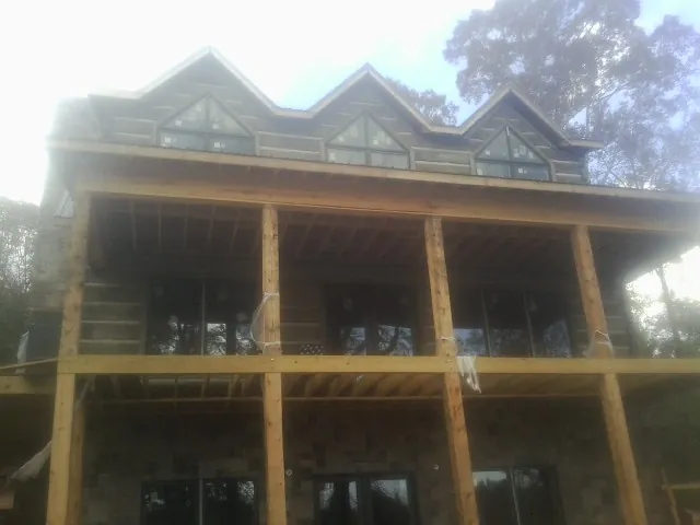Dormers and porch framing on a large log home under construction — Roof Coating work by our crew in Wallkill