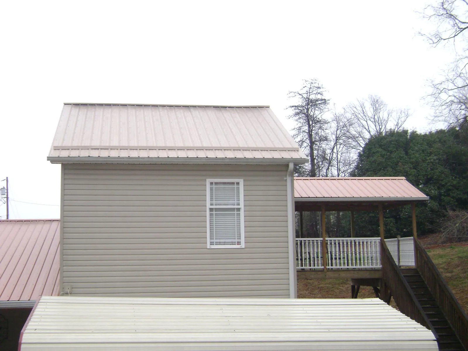 Tan metal roofs on a two story addition and attached porch, from a Roof Replacement job in Wallkill