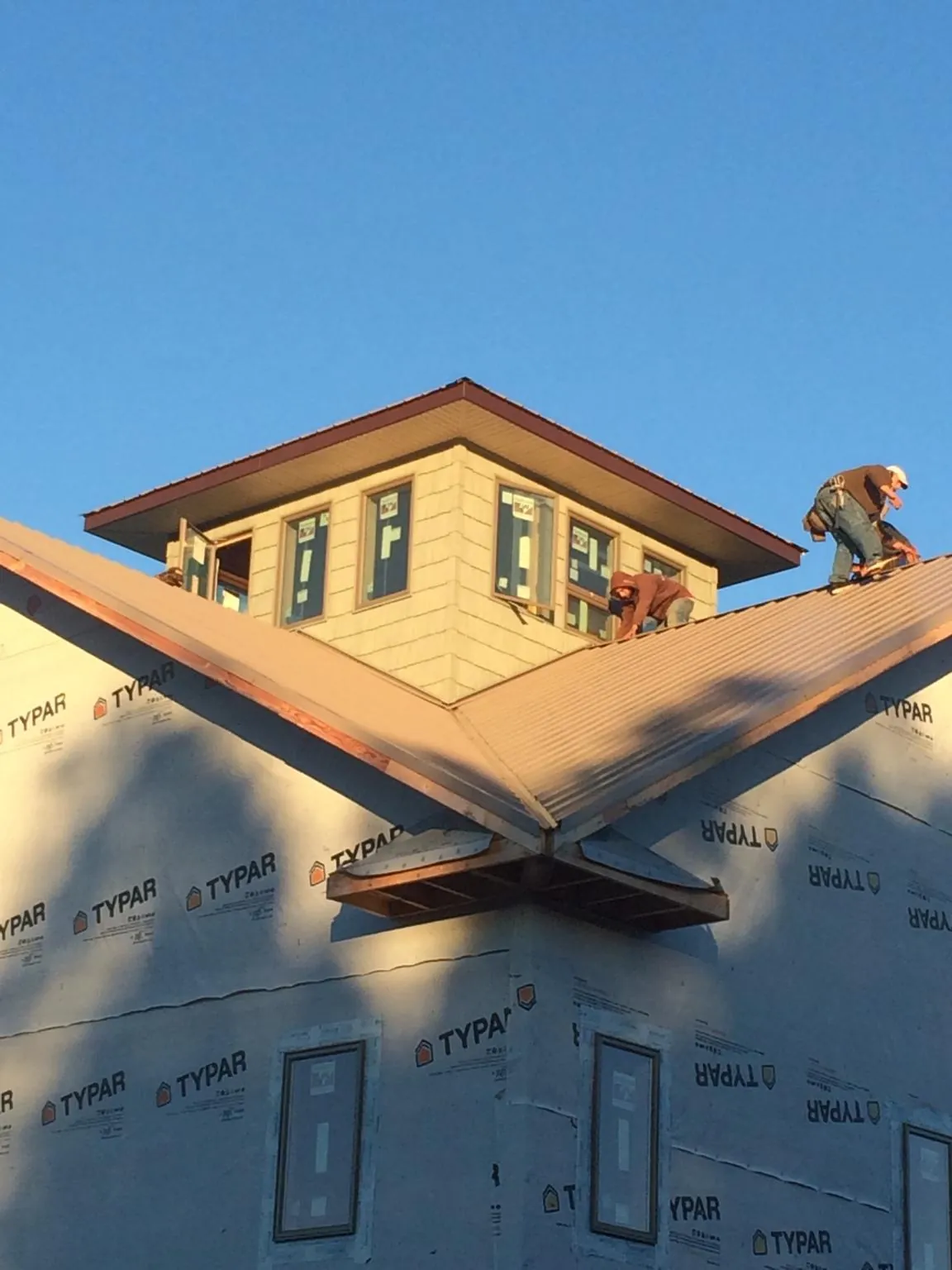 Roofers working around a rooftop cupola on a new metal roof at sunset — Roof Waterproofing in Wallkill by Roofing Brothers